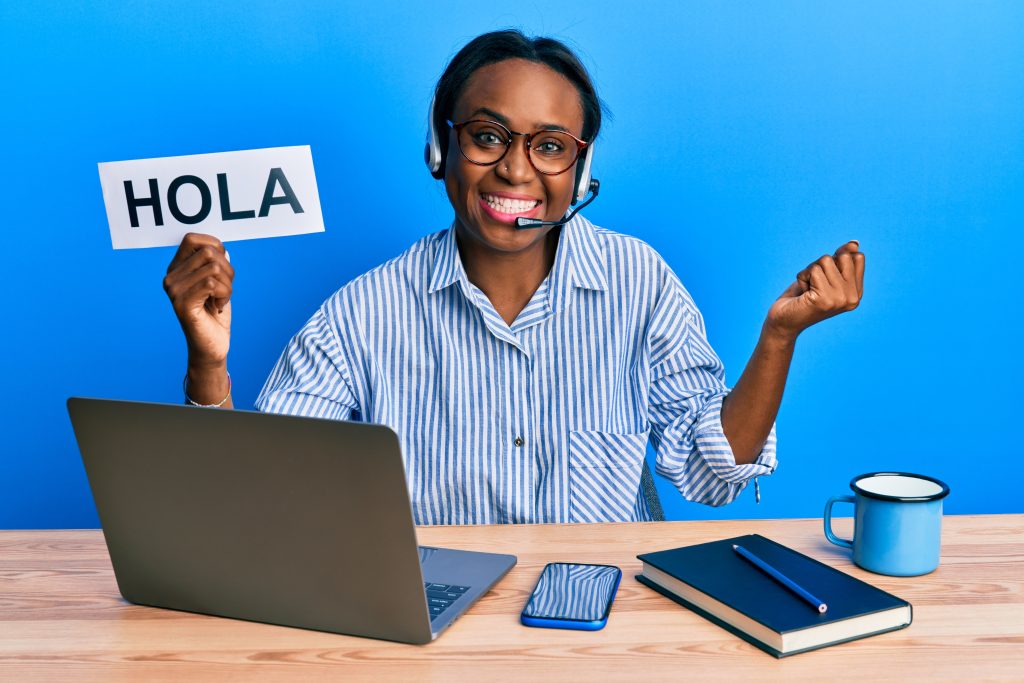 young african woman wearing operator headset holding hola word screaming proud, celebrating victory and success very excited with raised arm
